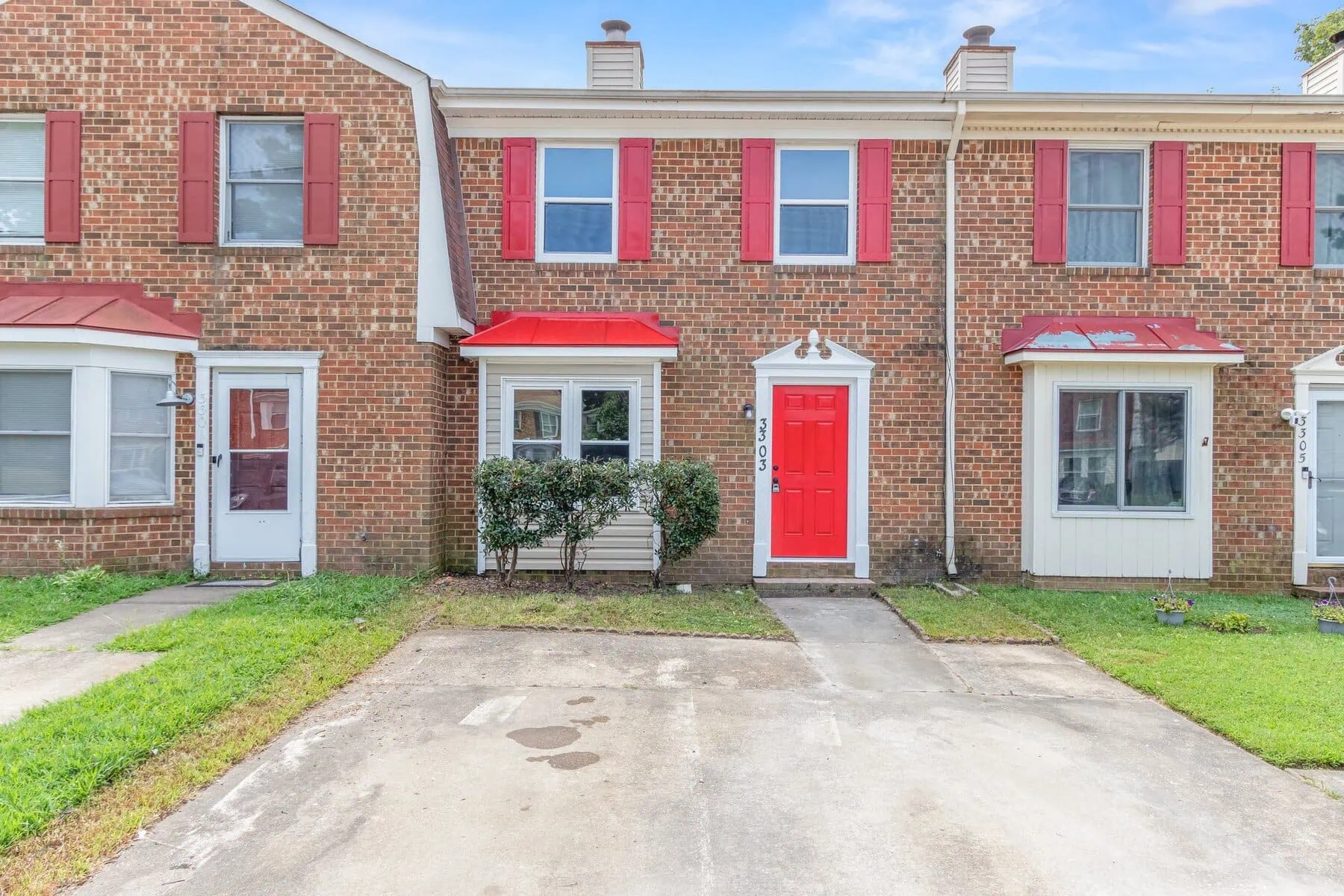 A brick home with red doors and a driveway