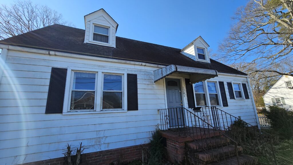 The front of a dirty white house that we bought for cash in Surry